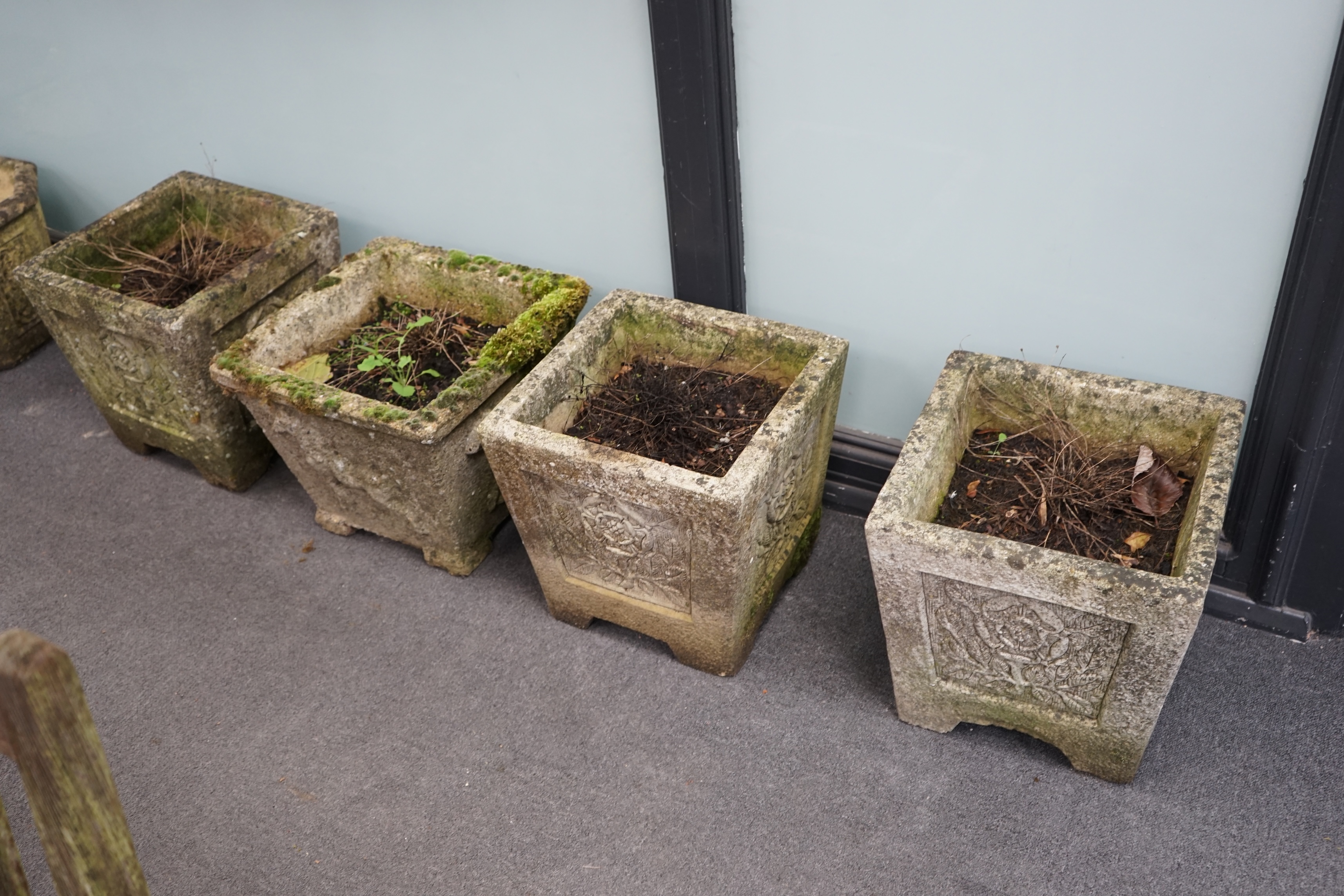 A set of three reconstituted stone garden planters, decorated with Tudor roses, 36cm sq., 37cm high, and a single square planter moulded in relief with a horse